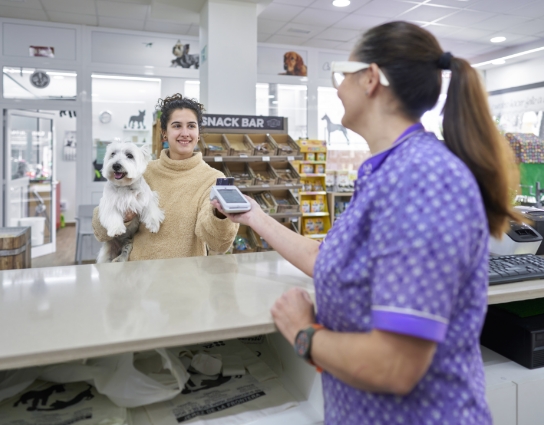 A pet owner paying at a vet practice counter